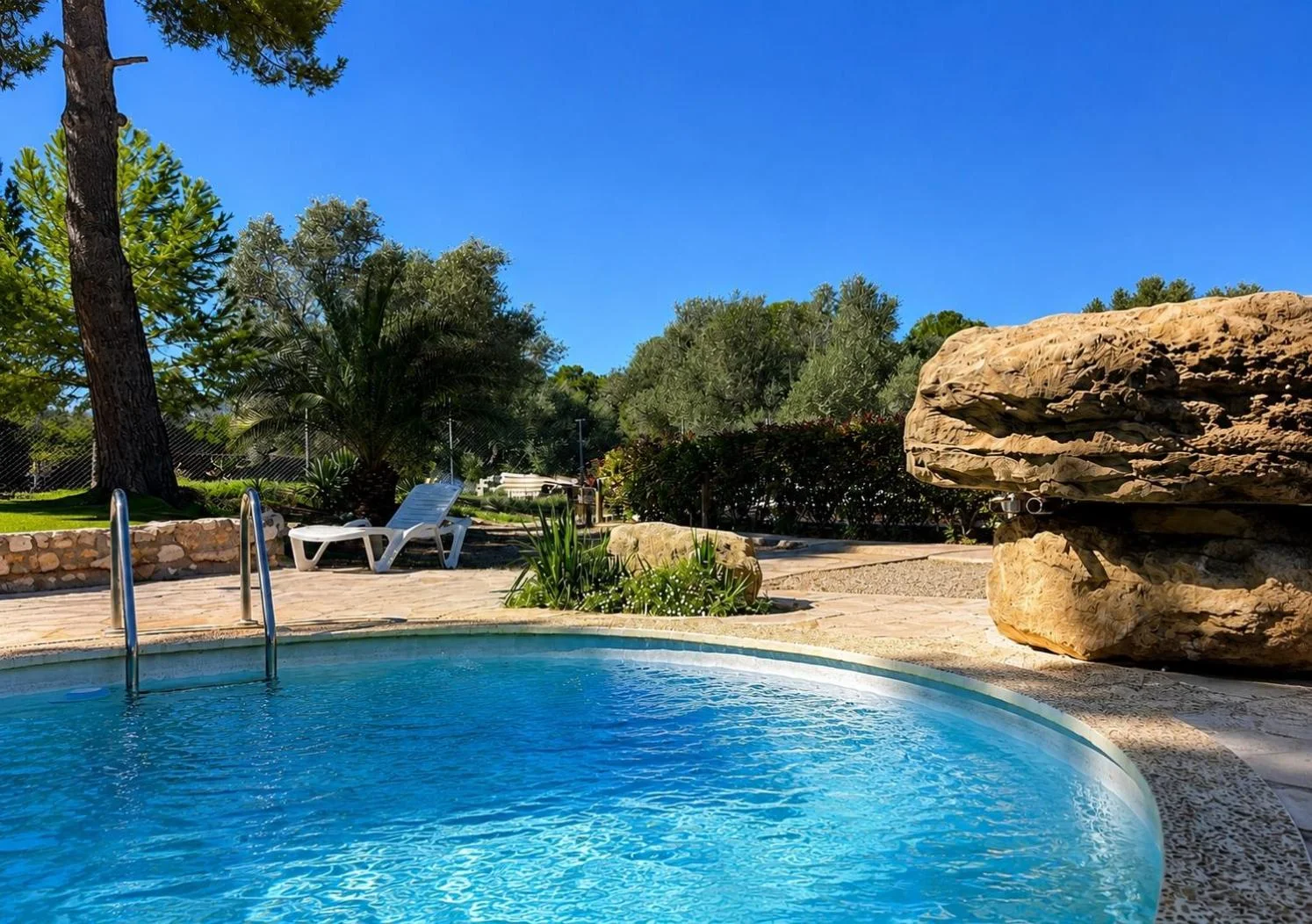Piscina al aire libre rodeada de pinos y roca